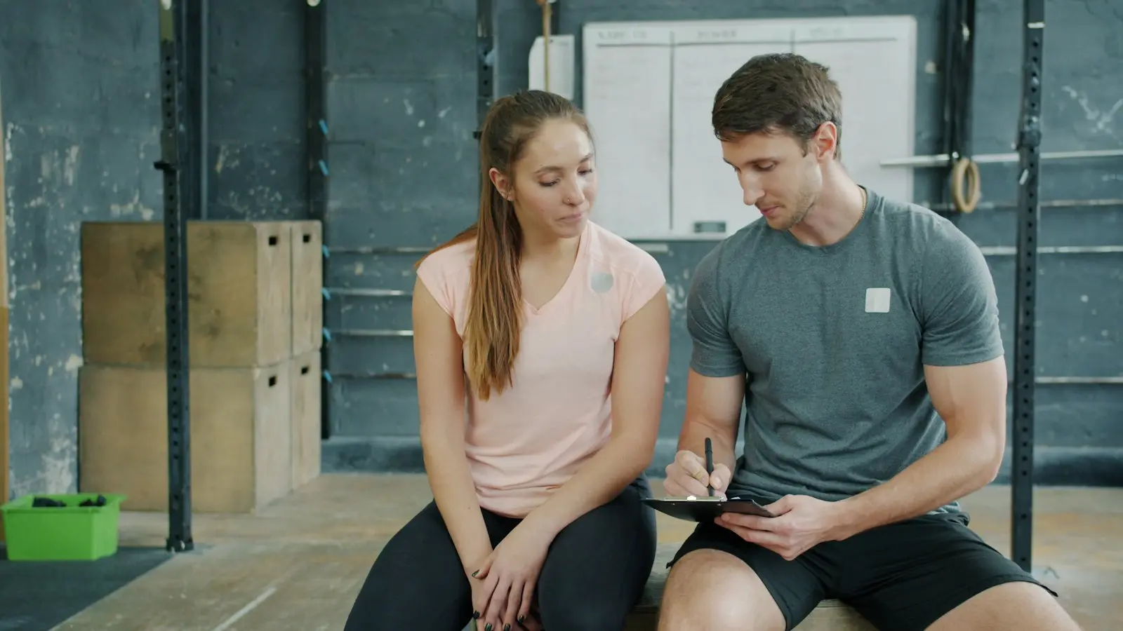 Trenér s klientkou procházejí na tabletu plán tréninku