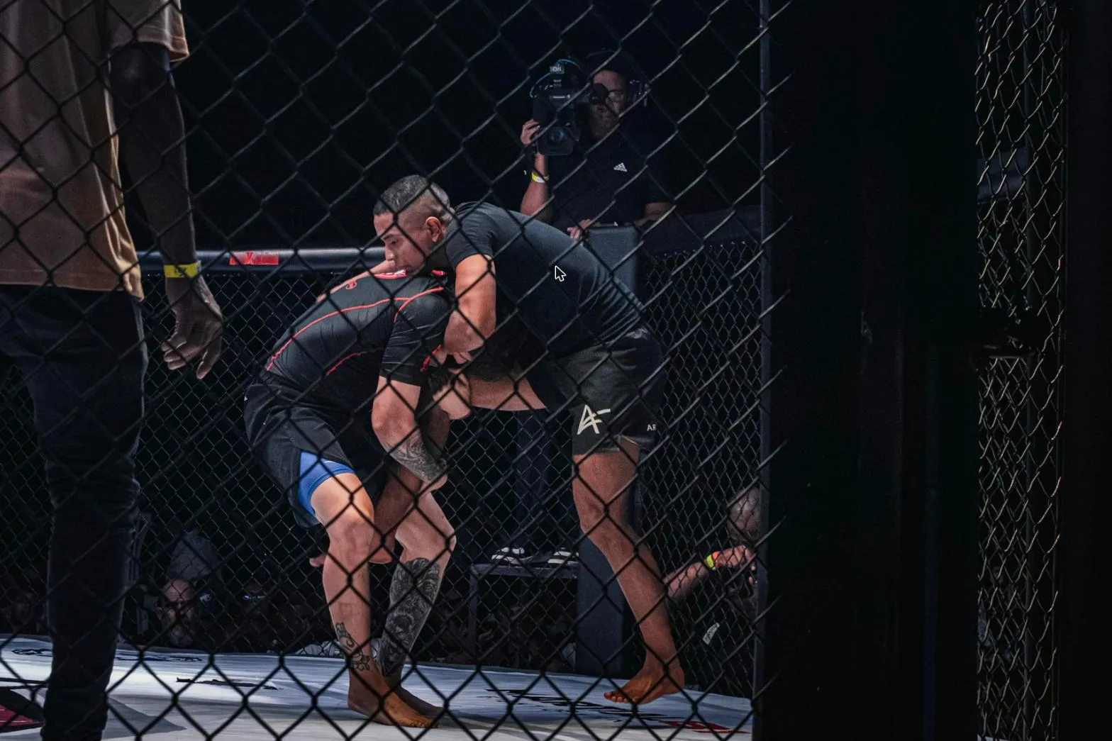 MMA v kleci: dva zápasníci v klinči u pletiva